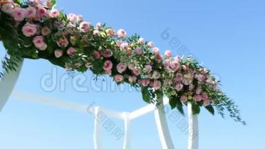 婚礼装饰，用玫瑰装饰的白色婚礼拱门，海滩上的婚礼，婚礼的准备